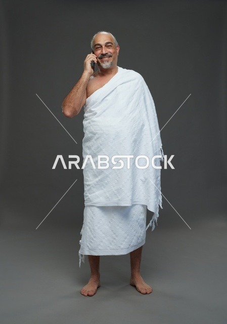 رجل سعودي بملابس الإحرام يتحدث عبر الهاتف الذكي