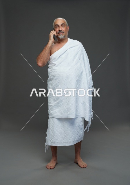 رجل سعودي بملابس الإحرام يتحدث بالهاتف الذكي في استوديو