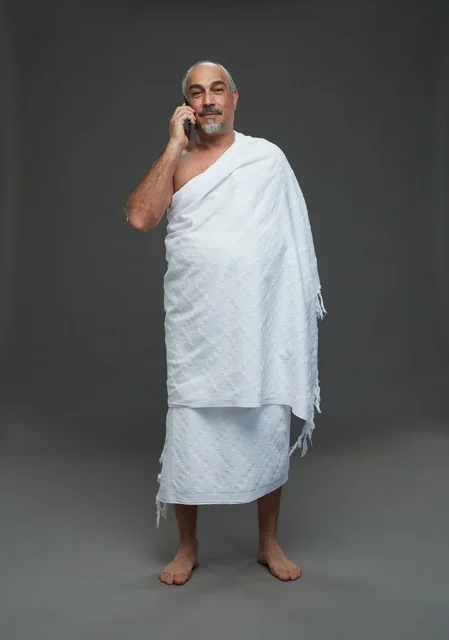 رجل سعودي بملابس الإحرام يتحدث بالهاتف الذكي في استوديو