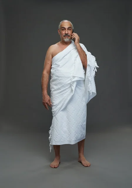 رجل سعودي بملابس الإحرام البيضاء يتحدث عبر الجوال