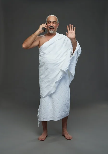 رجل سعودي بملابس الإحرام يتحدث بالهاتف الذكي