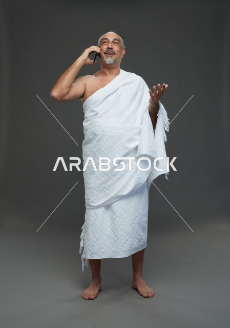 رجل سعودي بملابس الإحرام يتحدث بالهاتف الذكي