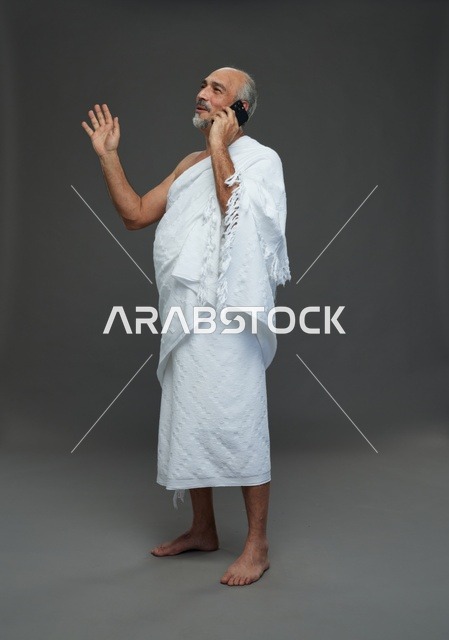 رجل سعودي بملابس الإحرام يتحدث بالهاتف في استوديو