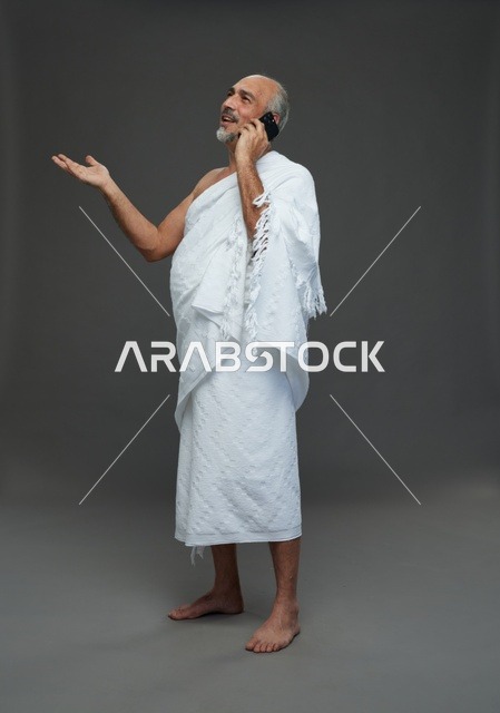 رجل سعودي بملابس الإحرام يستخدم هاتف ذكي في استوديو