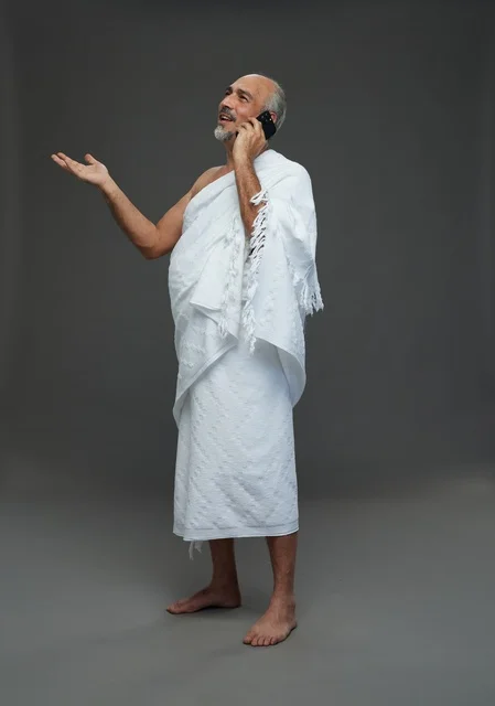 رجل سعودي بملابس الإحرام يستخدم هاتف ذكي في استوديو