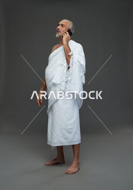 رجل سعودي بملابس الإحرام يتحدث عبر الهاتف الذكي