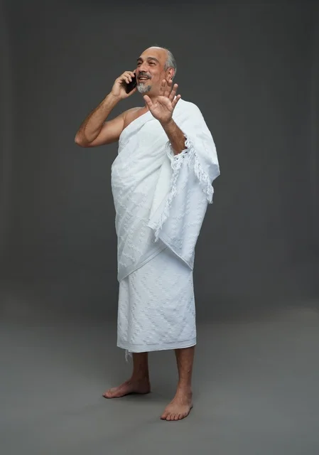 رجل سعودي بملابس الإحرام يتحدث بالهاتف في استوديو