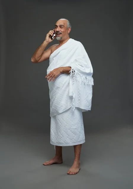 رجل سعودي بملابس الإحرام يستخدم الهاتف الذكي