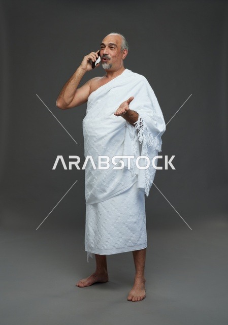 رجل سعودي بملابس الإحرام يتحدث بالهاتف الذكي