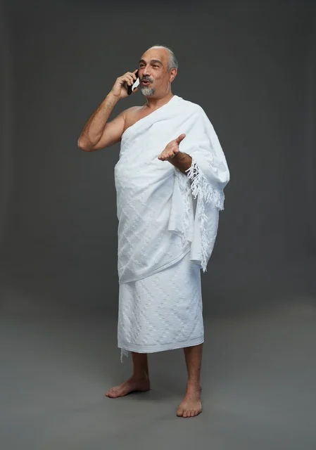 رجل سعودي بملابس الإحرام يتحدث بالهاتف الذكي