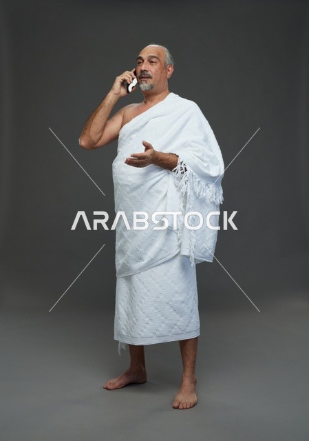 رجل سعودي بملابس الإحرام يتحدث عبر الهاتف الذكي