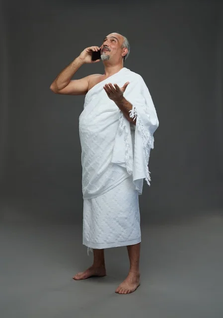 رجل سعودي بملابس الإحرام يتحدث بالهاتف الذكي