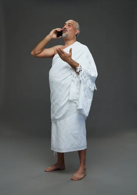 رجل سعودي بملابس الإحرام يتحدث بالهاتف الذكي