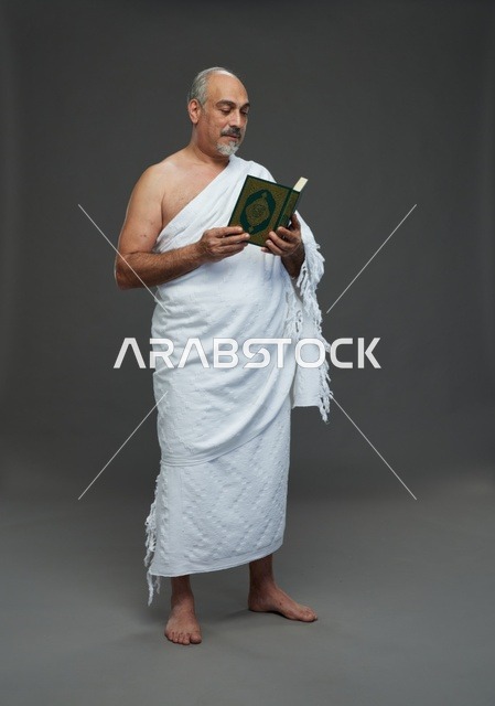 رجل سعودي بملابس الإحرام يقرأ القرآن الكريم