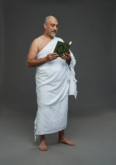 رجل سعودي بملابس الإحرام يقرأ القرآن الكريم