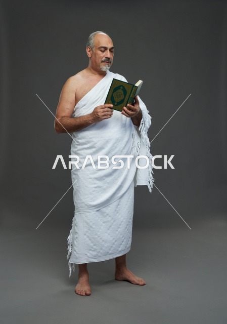 رجل سعودي بملابس الإحرام يقرأ القرآن الكريم