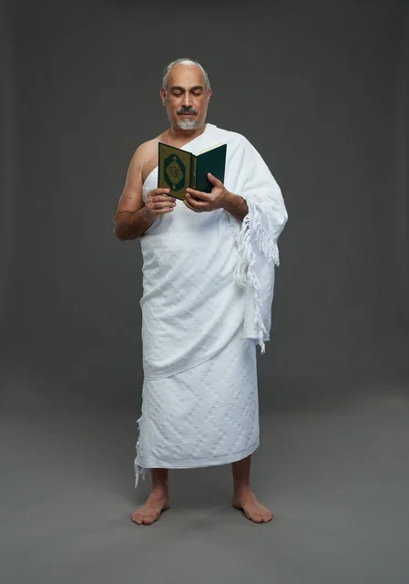 رجل سعودي بملابس الإحرام يقرأ القرآن الكريم في الاستوديو