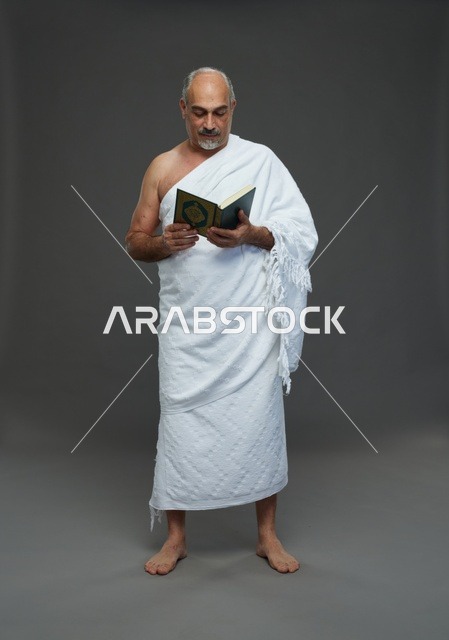 رجل سعودي بملابس الإحرام يقرأ القرآن الكريم في الاستوديو