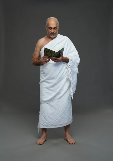 رجل سعودي بملابس الإحرام يقرأ القرآن الكريم في الاستوديو