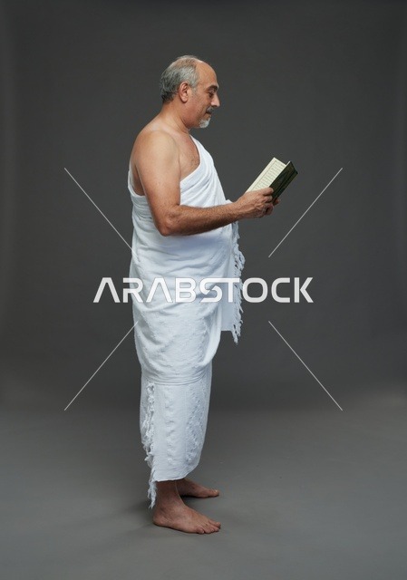 رجل سعودي بملابس الإحرام يقرأ القرآن الكريم