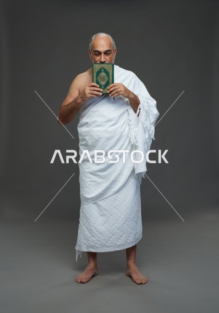 رجل سعودي بملابس الإحرام البيضاء يحمل القرآن الكريم