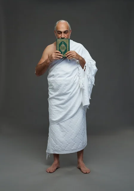 Saudi Man in White Ihram Holding Holy Quran in Studio