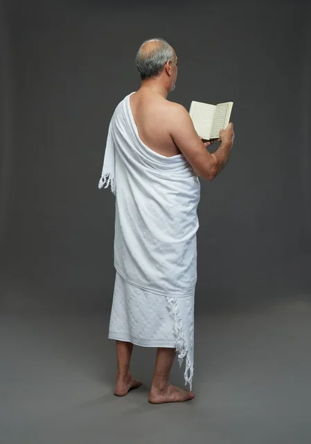 رجل سعودي بملابس الإحرام يقرأ القرآن الكريم