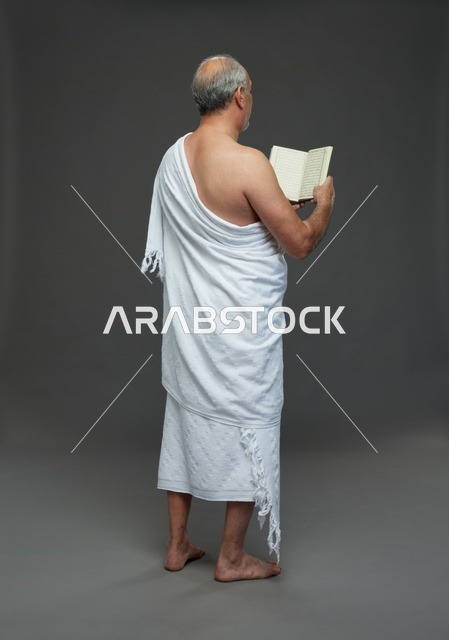 رجل سعودي بملابس الإحرام يقرأ القرآن الكريم