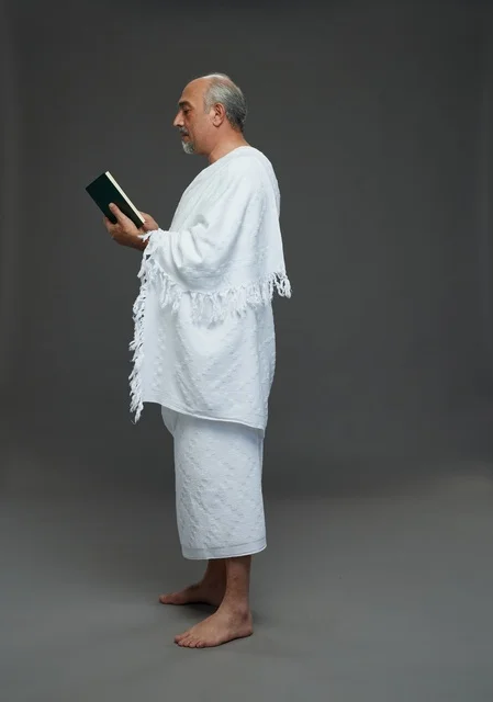 رجل سعودي بملابس الإحرام يقرأ القرآن الكريم في استوديو