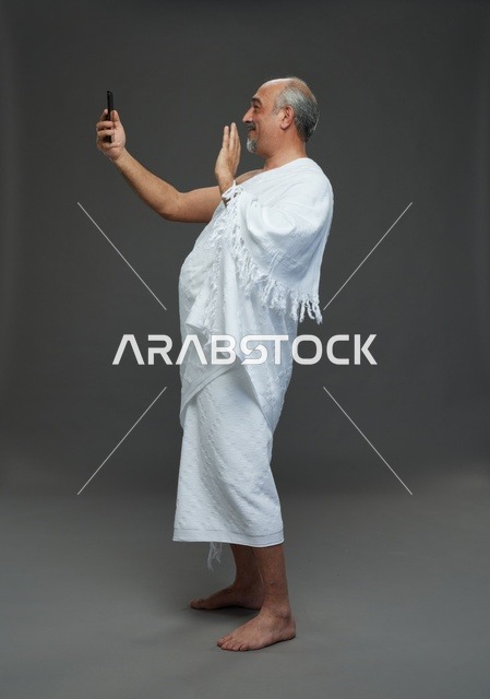 رجل سعودي بملابس الإحرام يلتقط سيلفي بالهاتف