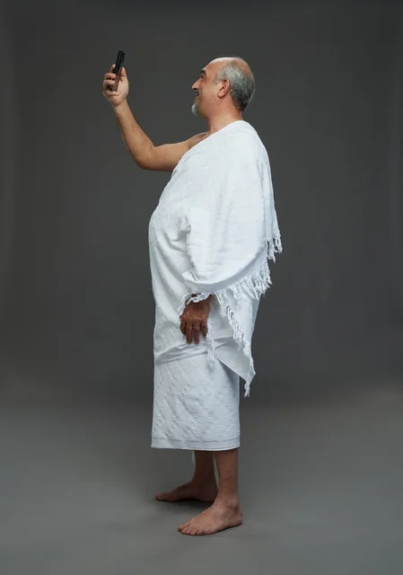 رجل سعودي بملابس الإحرام يلتقط سيلفي بالهاتف