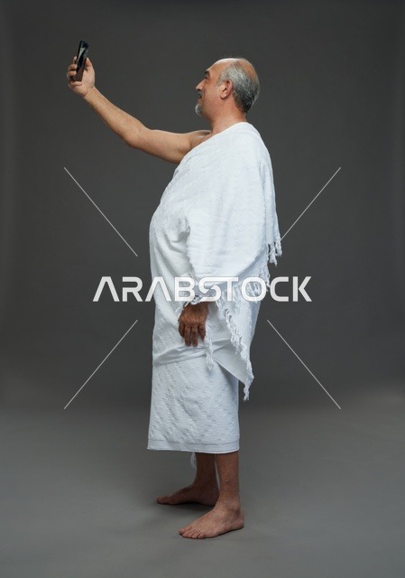 رجل سعودي بملابس الإحرام يلتقط سيلفي بالهاتف الذكي