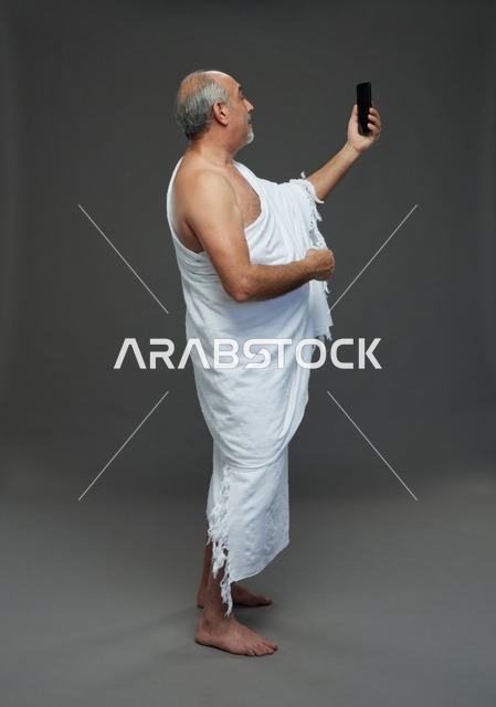 رجل سعودي بملابس الإحرام يلتقط سيلفي بالهاتف الذكي
