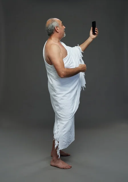Saudi Man in Ihram Taking Selfie with Smartphone on Grey