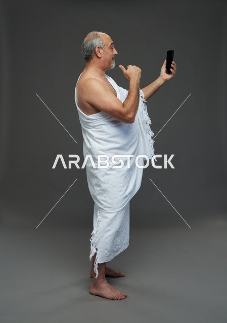رجل سعودي بملابس الإحرام يلتقط سيلفي بالهاتف
