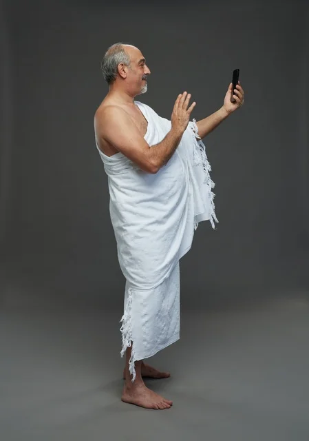 رجل سعودي بملابس الإحرام يستخدم هاتف ذكي في استوديو