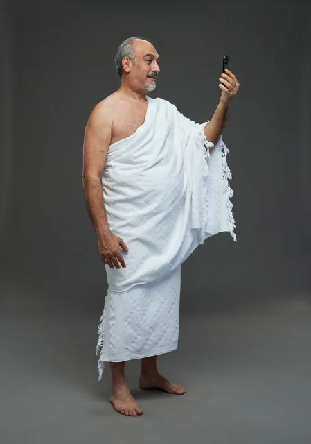 رجل سعودي بملابس الإحرام يستخدم الهاتف الذكي