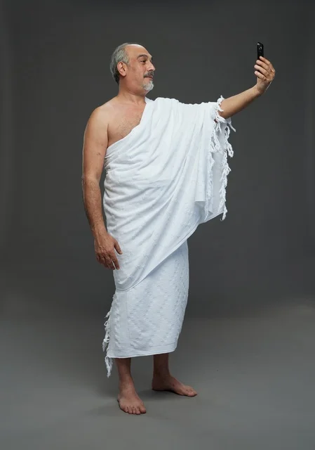 Saudi man in Ihram taking a selfie with smartphone