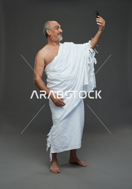 رجل مسلم سعودي بملابس الإحرام يلتقط سيلفي بالهاتف الذكي