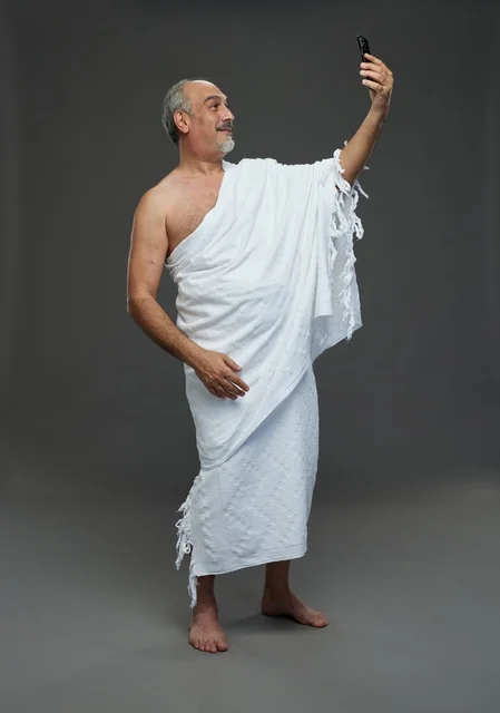 رجل سعودي بملابس الإحرام يلتقط سيلفي بالهاتف