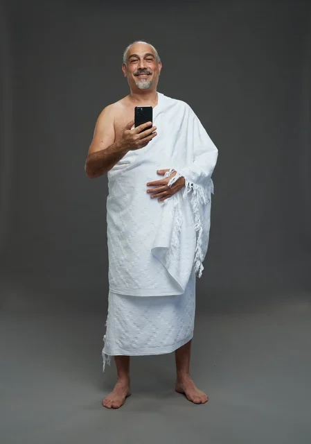 رجل سعودي بملابس الإحرام يلتقط سيلفي بالهاتف