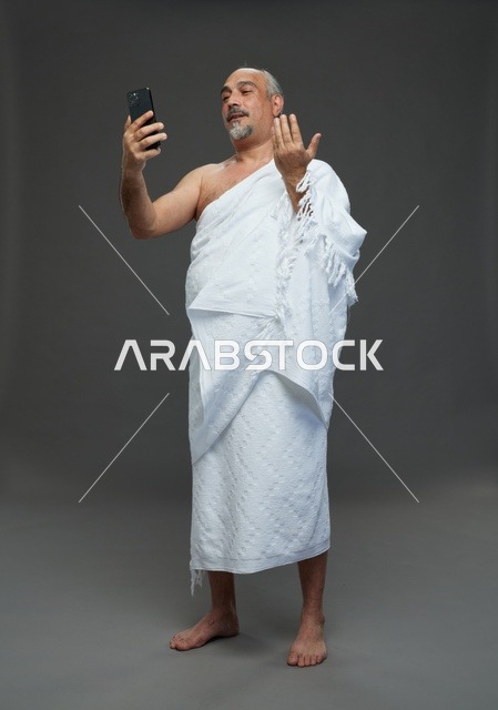 رجل سعودي بملابس الإحرام يلتقط سيلفي باستخدام الهاتف الذكي