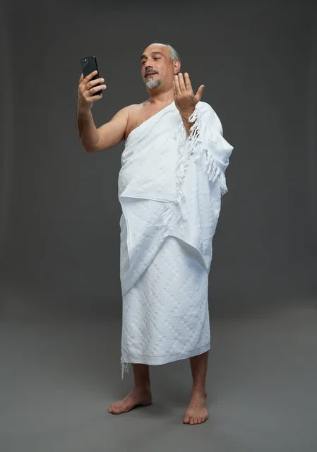 رجل سعودي بملابس الإحرام يلتقط سيلفي باستخدام الهاتف الذكي