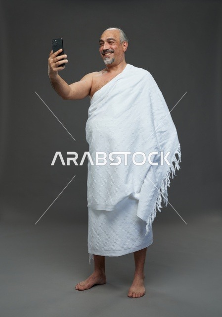 رجل سعودي بملابس الإحرام يلتقط سيلفي بالهاتف الذكي
