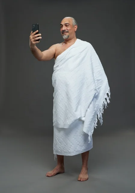 رجل سعودي بملابس الإحرام يلتقط سيلفي بالهاتف