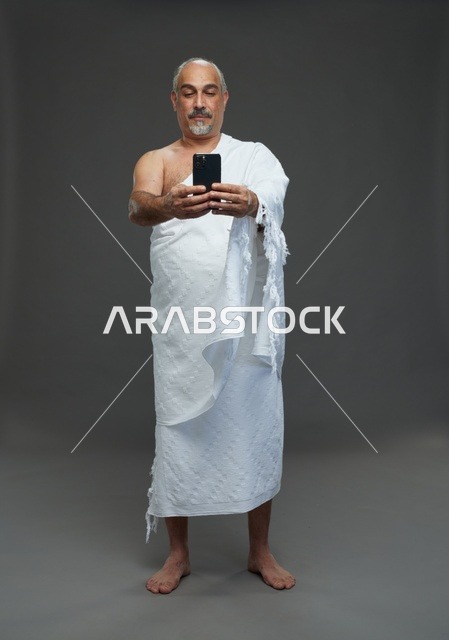 رجل سعودي بملابس الإحرام يلتقط سيلفي بالهاتف
