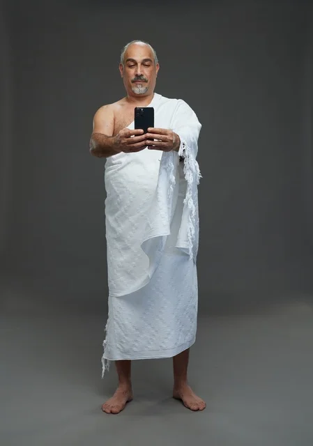 رجل سعودي بملابس الإحرام يلتقط سيلفي بالهاتف
