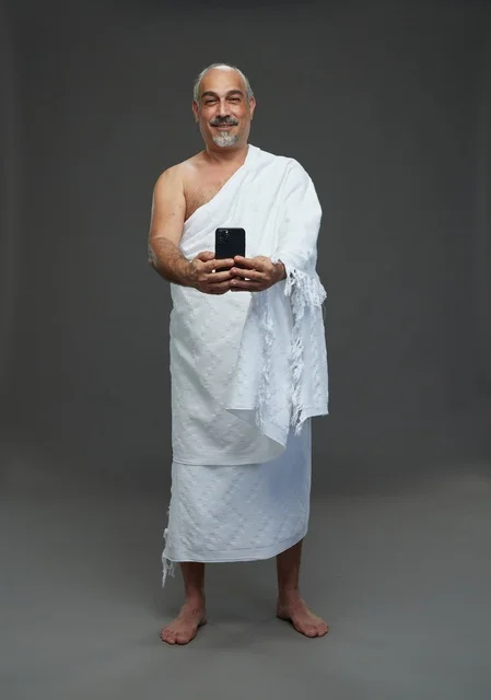 رجل سعودي بملابس الإحرام يلتقط سيلفي بالهاتف