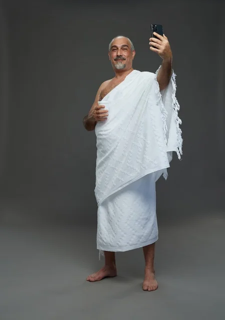 رجل سعودي يرتدي ملابس الإحرام يلتقط سيلفي بالهاتف