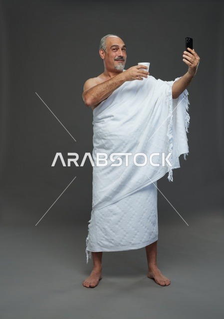 رجل سعودي بملابس الإحرام يلتقط سيلفي بالهاتف